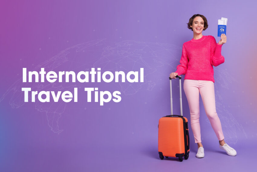 International Travel tips with a girl in a pink sweater holding up her passport smiling and holding an orange carry on luggage